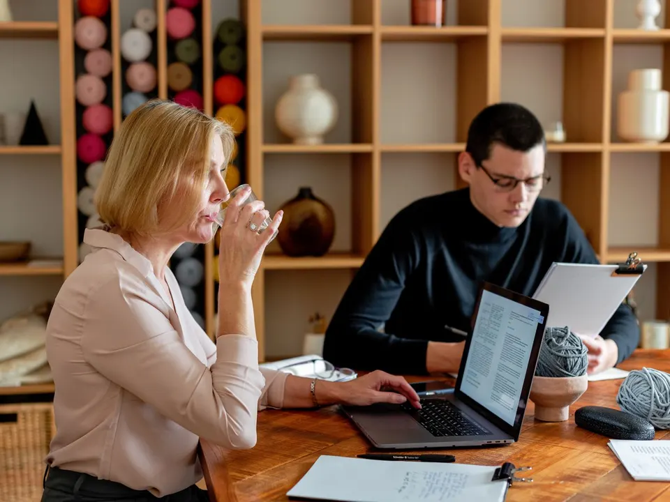 Woman drinking water while working at a shared office table